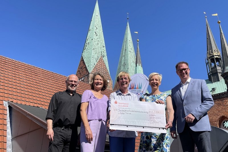 Von links: Dompastor Martin Klatt, Fundraiserin Heike Reimann, Projekt-Leiterin Cornelia Schäfer, Petra Ulrich und Bürgermeister Jan Lindenau bei der Scheckübergabe auf dem Dach des Rathauses. Im Hintergrund sind die Türme von St. Marien zu sehen.