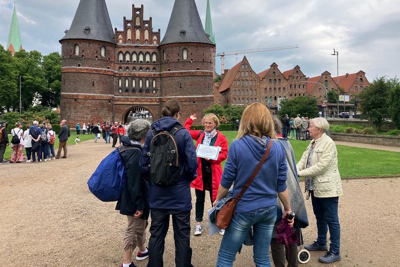 Stadtführerin und Organisatorin Stephanie Ullrich begrüßt Gäste vor dem Holstentor in Lübeck.